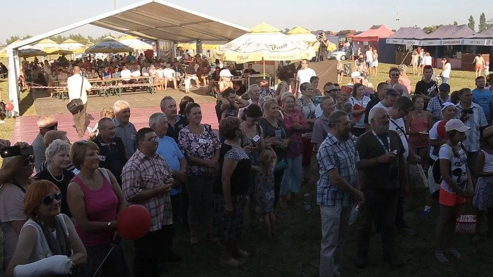 Publiczność przed sceną, a w tle namioty i stoły XIII Festynu w Dobrzykowicach.