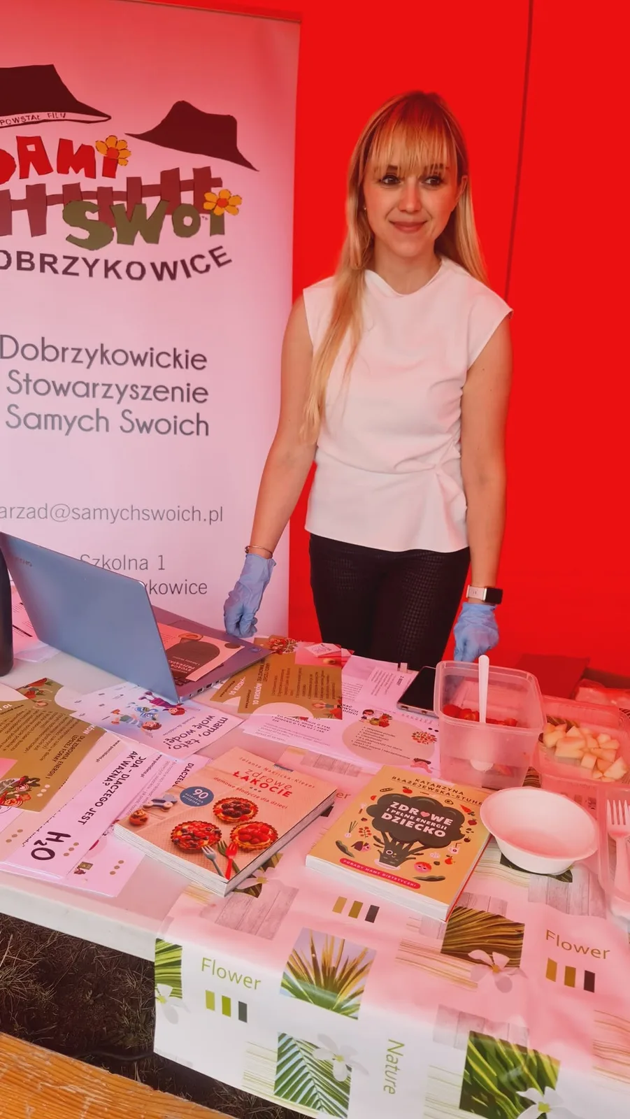Prowadząca przy stole z owocami i materiałami edukacyjnymi o żywieniu.