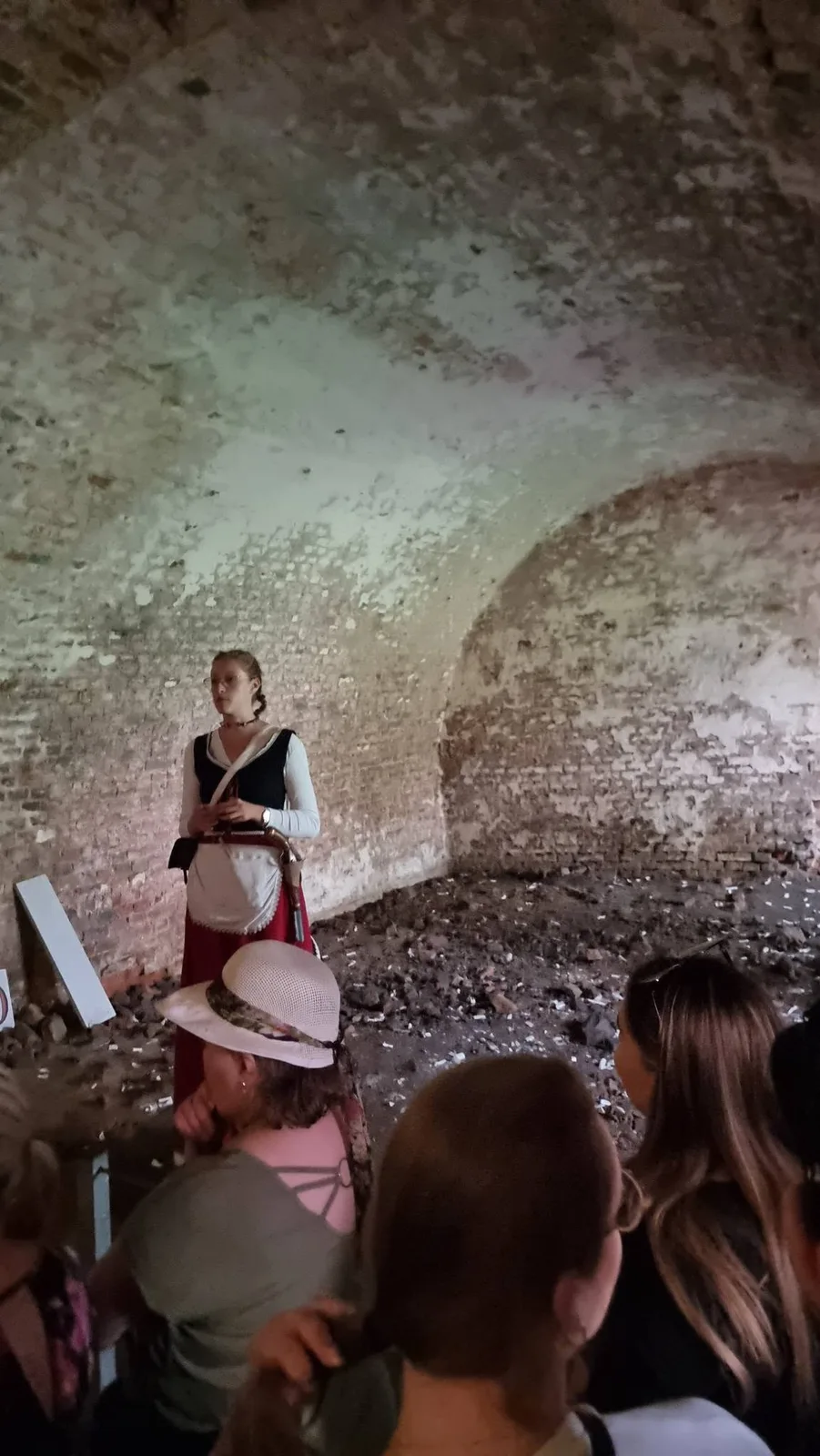 Przewodniczka w historycznym stroju opowiada grupie o twierdzy.