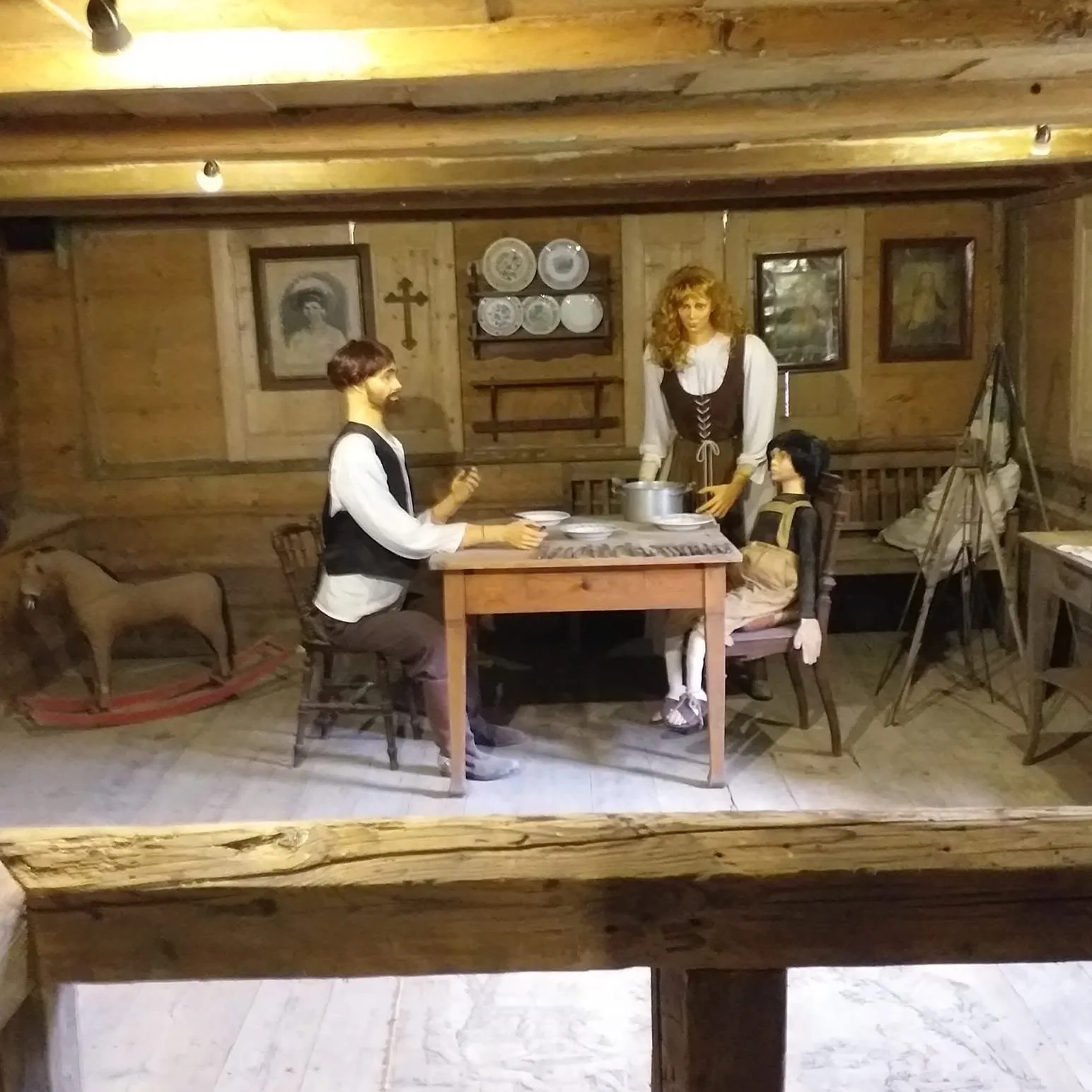 Ekspozycja dawnego domowego wnętrza z postaciami przy stole w muzeum w Pławnej.
